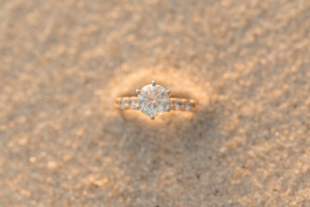 Solitaire engagement ring in the sand on the beach 