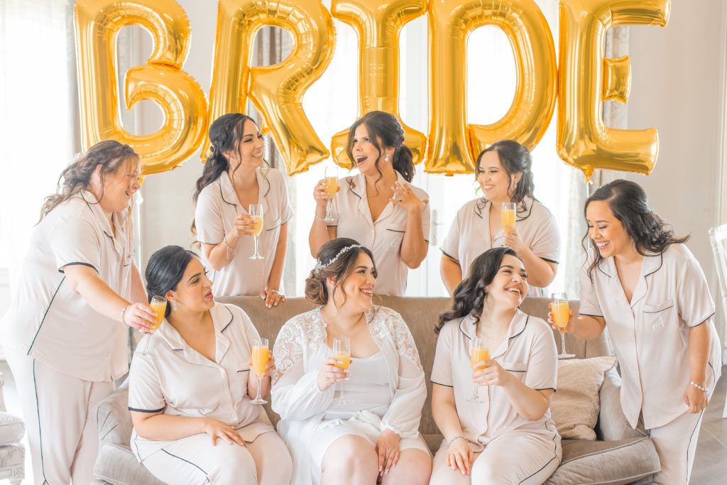 light and airy new jersey wedding photography of bride getting ready in bridal suite at the park chateau with matching bridesmaids pajamas 